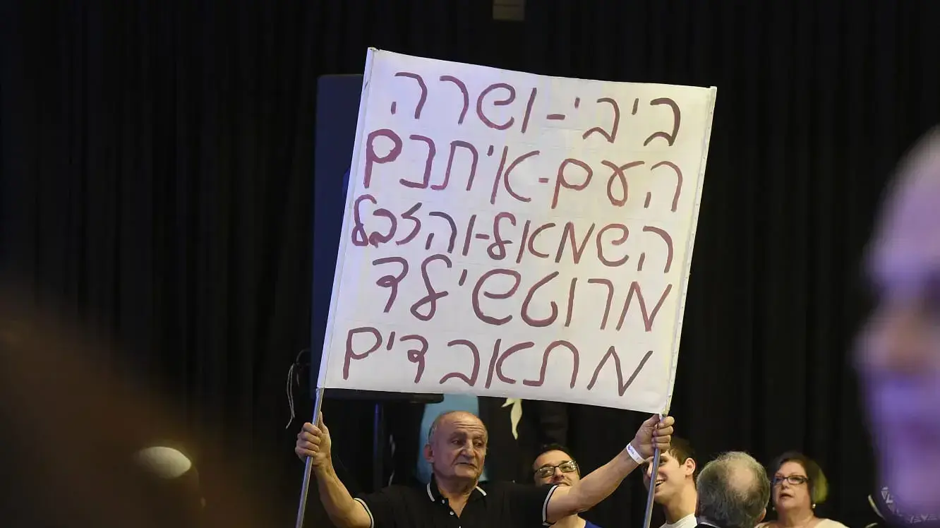 מפגין נושא שלט תמיכה בבנימין ושרה נתניהו בהרמת כוסית של הליכוד לחנוכה מפגין נושא שלט תמיכה בבנימין ושרה נתניהו בהרמת כוסית של הליכוד לחנוכה