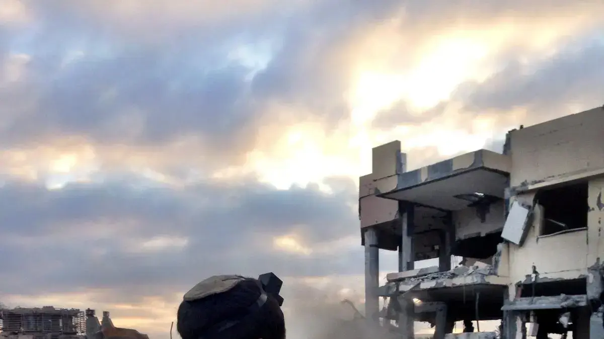 לוחם מתפלל על רקע המרפאה ההרוסה 2 לוחם מתפלל על רקע המרפאה ההרוסה 2
