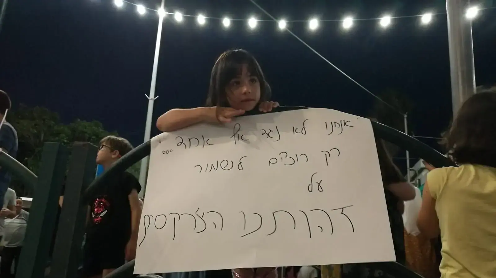 תושבת כפר כמא אוחזת שלט ובהפגנה נגד המרכז על הקרקע בו זכתה משפחה שלא מהעדה הצ'רקסית. 10 ביולי 2019 תושבת כפר כמא אוחזת שלט ובהפגנה נגד המרכז על הקרקע בו זכתה משפחה שלא מהעדה הצ'רקסית. 10 ביולי 2019