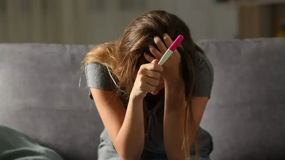 אישה עצובה מחזיקה בדיקת היריון אישה עצובה מחזיקה בדיקת היריון