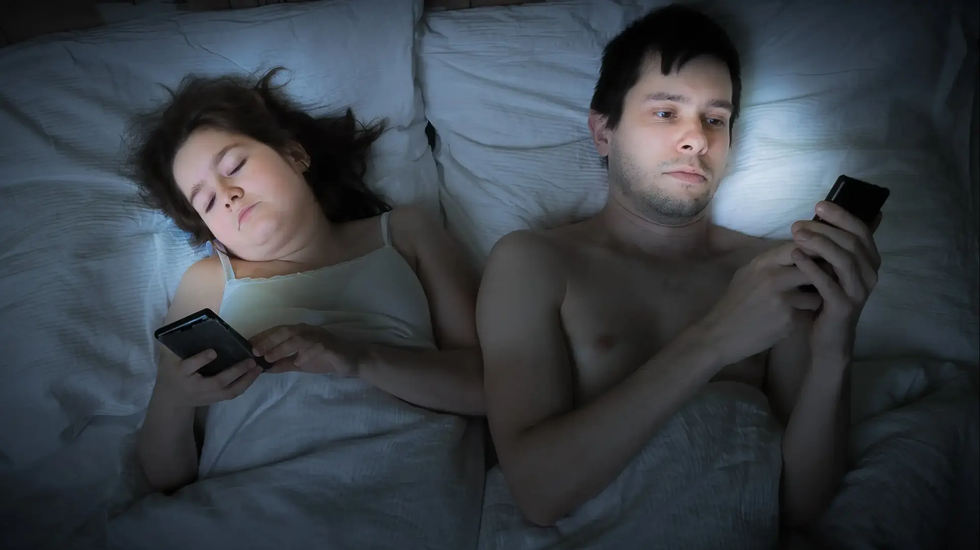 בני זוג במיטה עם טלפונים ניידים בני זוג במיטה עם טלפונים ניידים