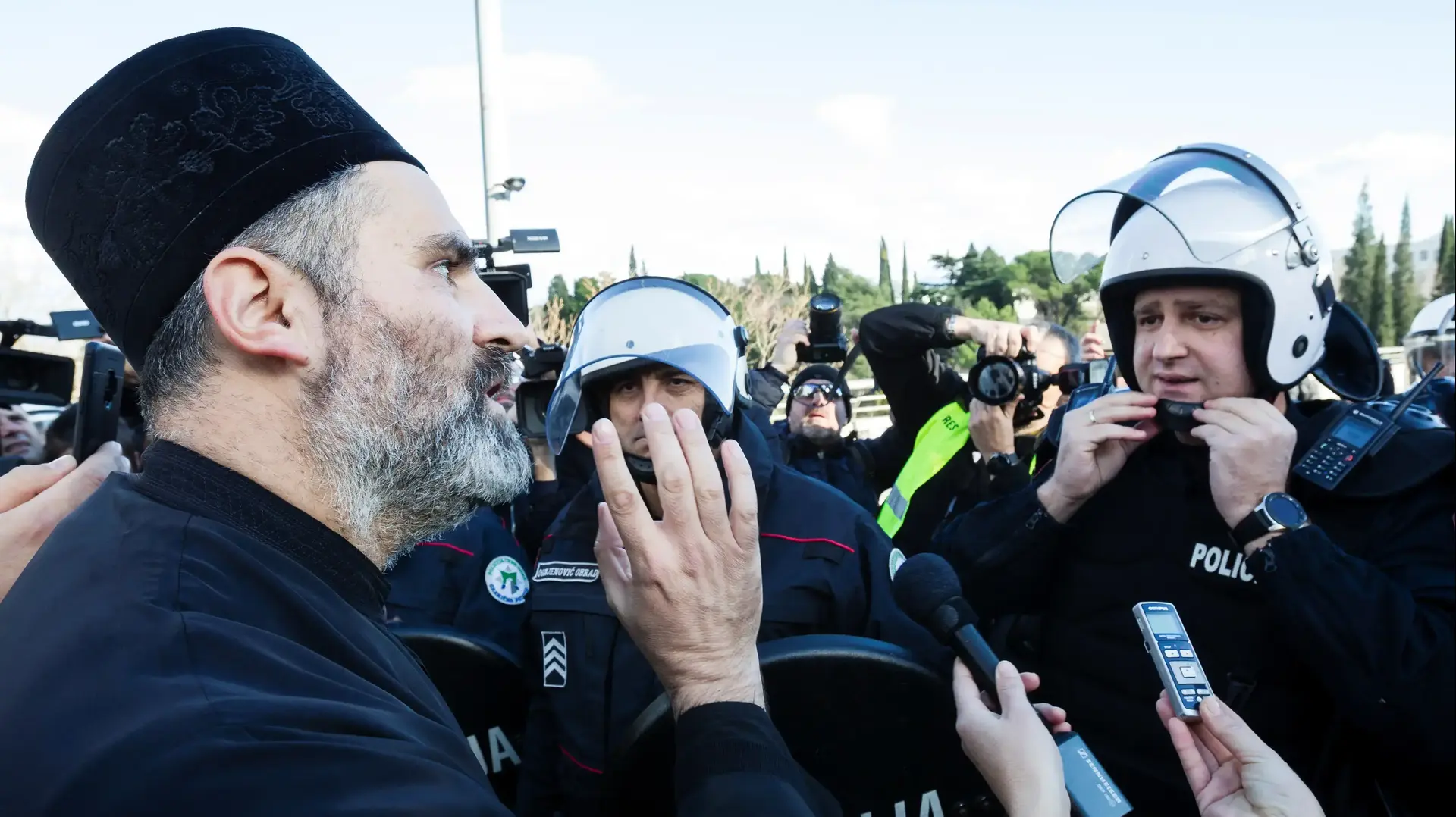 כומר אורתודוכסי סרבי משוחח עם שוטר בהפגנה מול הפרלמנט של מונטנגרו, 26 בדצמבר 2019 כומר אורתודוכסי סרבי משוחח עם שוטר בהפגנה מול הפרלמנט של מונטנגרו, 26 בדצמבר 2019
