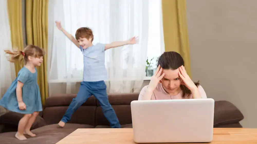 אישה מנסה לעבוד מהבית בזמן שהילדים שלה משתוללים בבית אישה מנסה לעבוד מהבית בזמן שהילדים שלה משתוללים בבית