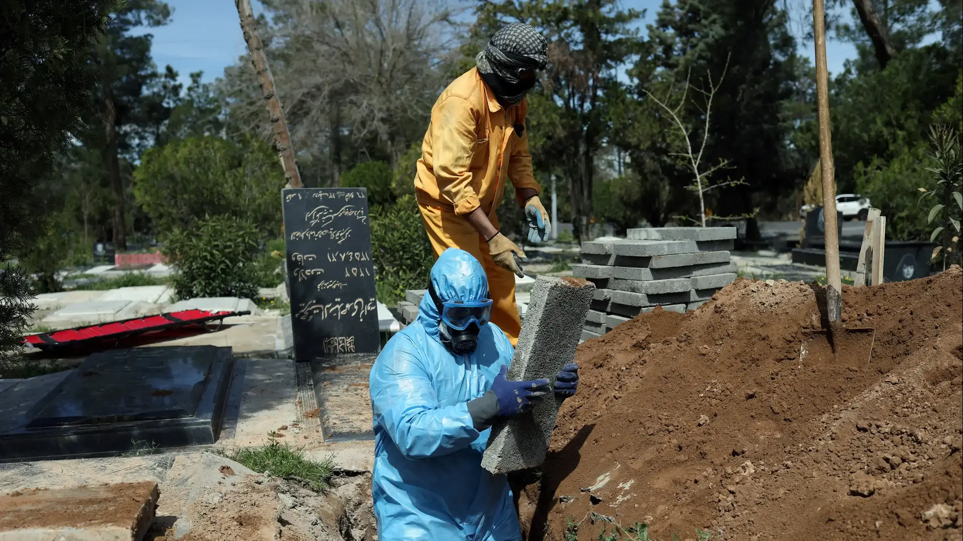 גברים לובשים חליפה לצורך התגוננות מנגיף הקורונה במהלך קבורותו של עיתונאי איראני שהלך לעולמו בעקבות הדבקותו בנגיף הקורונה 24 במרץ 2020 גברים לובשים חליפה לצורך התגוננות מנגיף הקורונה במהלך קבורותו של עיתונאי איראני שהלך לעולמו בעקבות הדבקותו בנגיף הקורונה 24 במרץ 2020