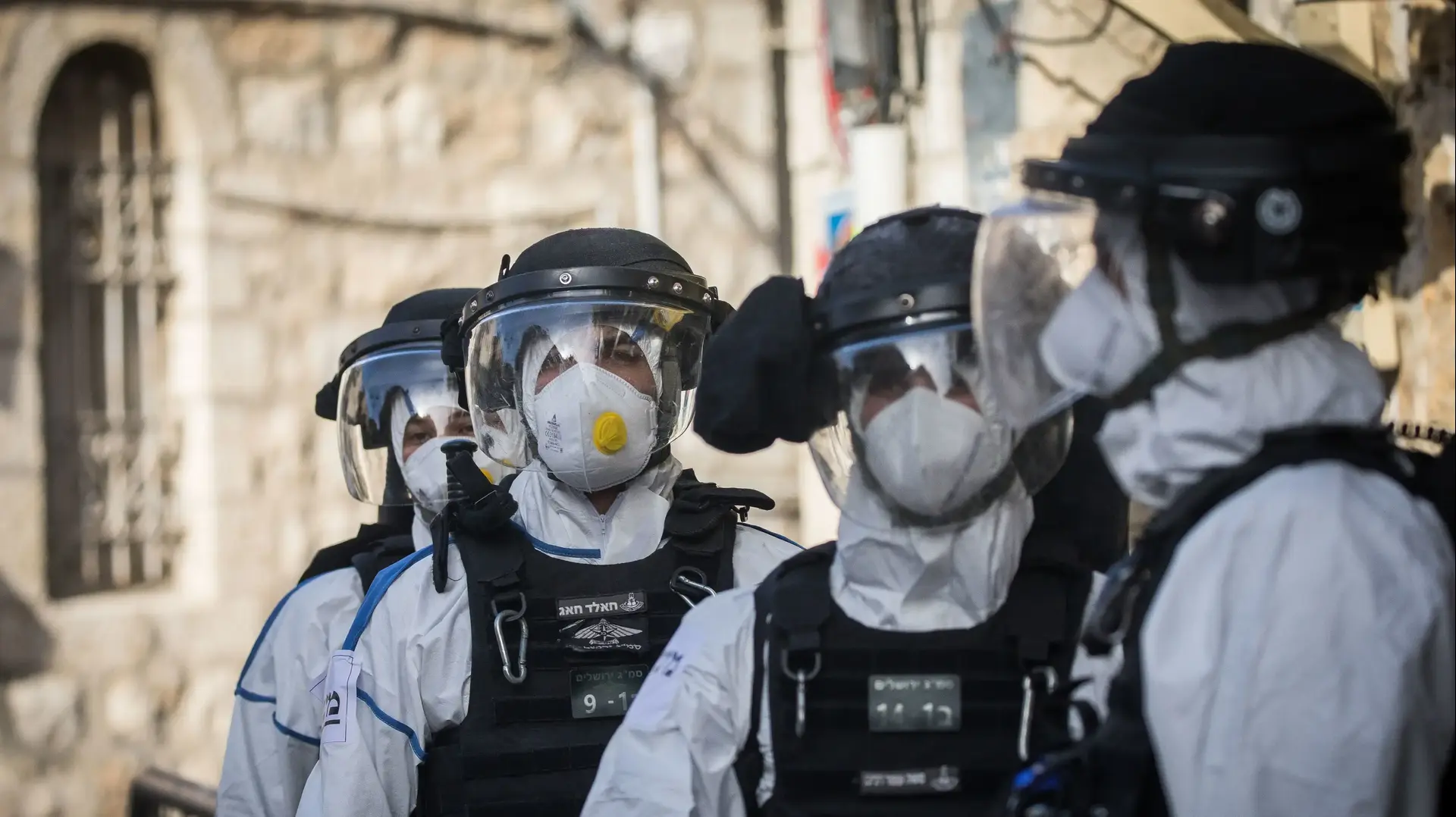 שוטרים ממוגנים עם חליפה מנגיף הקורונה לאחר מעצרו של אדם שהפר את תנאי הבידוד בשכונת מאה שערים בירושלים 6 באפריל 2020