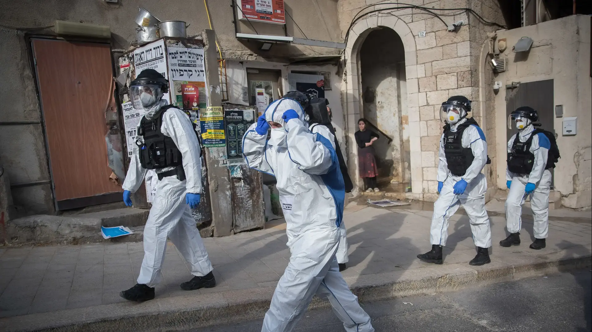 שוטרים ממוגנים עם חליפה מנגיף הקורונה לאחר מעצרו של אדם שהפר את תנאי הבידוד בשכונת מאה שערים בירושלים 6 באפריל 2020