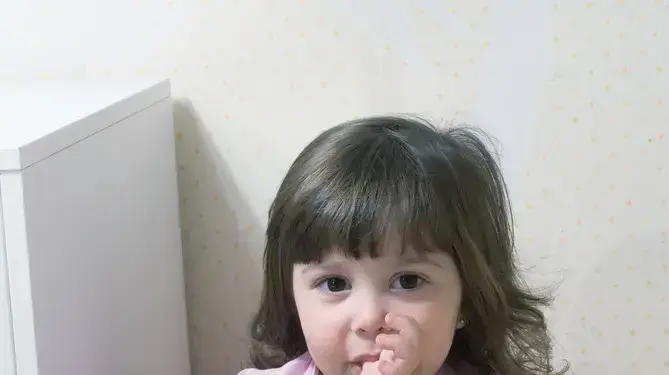ילדה מוצצת אצבע ומחזיקה שמיכי