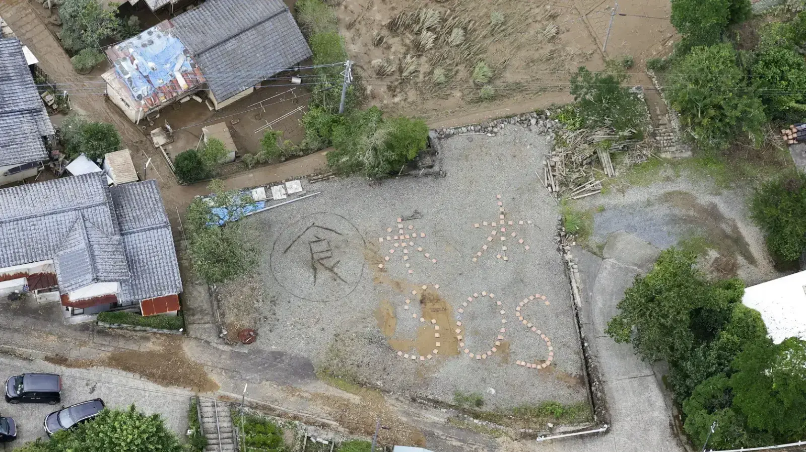 כתובת "אורז, מים SOS" בכפר קומה, קוממוטו, יפן, אחרי שיטפונות באזור, 5 ביולי 2020 כתובת "אורז, מים SOS" בכפר קומה, קוממוטו, יפן, אחרי שיטפונות באזור, 5 ביולי 2020