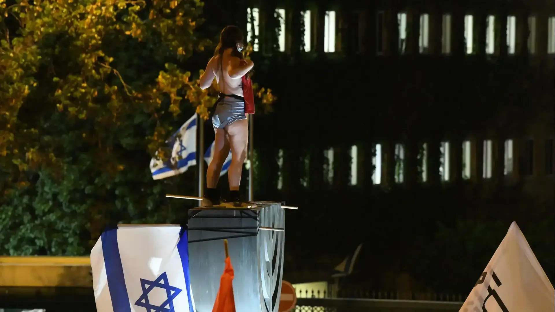 המחאות בירושלים: מפגינה חשופת חזה תועדה על סמל המנורה מול הכנסת, 22 ביולי 2020. צילום: ראובן קסטרו המחאות בירושלים: מפגינה חשופת חזה תועדה על סמל המנורה מול הכנסת, 22 ביולי 2020. צילום: ראובן קסטרו