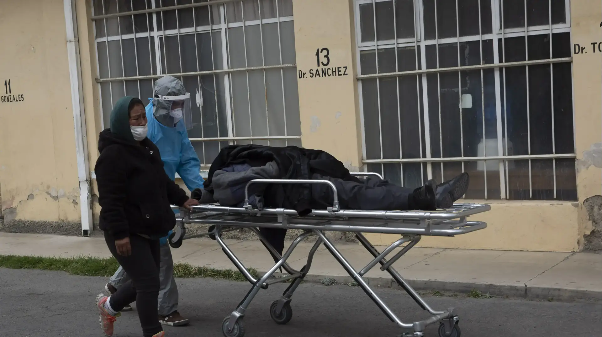עובד בריאות ממוגן דוחף באלונקה גופה של גבר למקום בו יילקח על ידי בית הלוויות מחוץ לבית החולים. לה פז, בוליביה, 23 ביולי 2020. עובד בריאות ממוגן דוחף באלונקה גופה של גבר למקום בו יילקח על ידי בית הלוויות מחוץ לבית החולים. לה פז, בוליביה, 23 ביולי 2020.