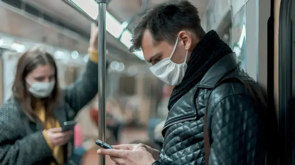 נוסעים ברכבת התחתית עוטים מסיכות פה ואף ומביטים בטלפונים הסלולריים שלהם נוסעים ברכבת התחתית עוטים מסיכות פה ואף ומביטים בטלפונים הסלולריים שלהם