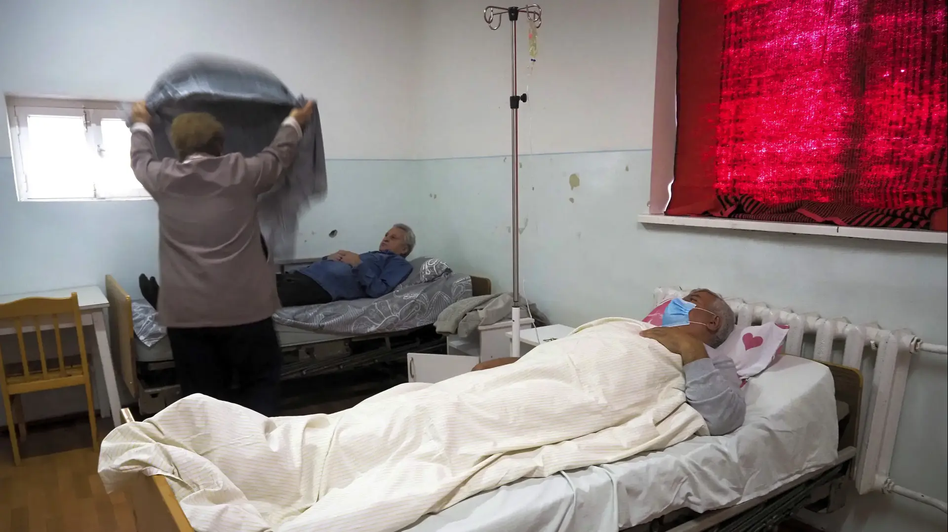 אישה מכסה את בעלה אשר נחשד כי מי שפיתח תסמינים לנגיף הקורונה במרפאה למחלות זיהומיות באזור הבדלני בנגורנו קרבאך, 20 באוקטובר 2020