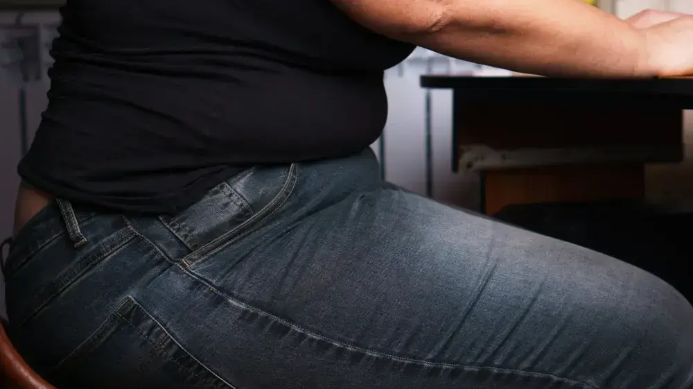 אישה עם עודף משקל יושבת ליד שולחן עבודה ומחשב אישה עם עודף משקל יושבת ליד שולחן עבודה ומחשב
