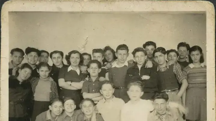 המורה לעברית חנה אייזנשטיין (בידיים שלובות) מוקפת בתלמידיה בכפר הילדים "אילניה". אפלדורן, הולנד 1947 המורה לעברית חנה אייזנשטיין (בידיים שלובות) מוקפת בתלמידיה בכפר הילדים "אילניה". אפלדורן, הולנד 1947