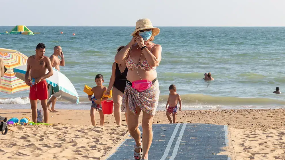 אישה עם מסיכה על חוף הים בפונטה אומבריה, ספרד, יולי 2020 אישה עם מסיכה על חוף הים בפונטה אומבריה, ספרד, יולי 2020