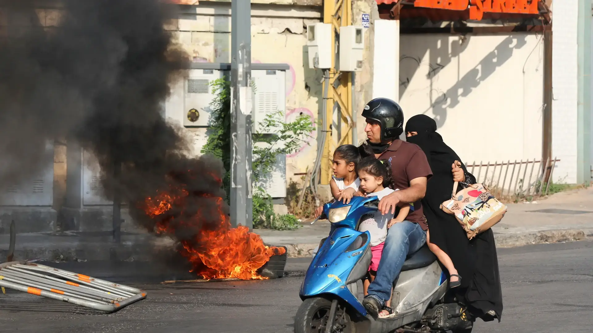 אופנוע חולף על צמיג בוער במהלך הפגנה של קרובי קורבנות האסון בנמל ביירות, סמוך לארמון הנשיאות של לבנון, 14 ביולי 2021 אופנוע חולף על צמיג בוער במהלך הפגנה של קרובי קורבנות האסון בנמל ביירות, סמוך לארמון הנשיאות של לבנון, 14 ביולי 2021