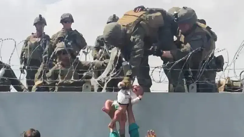 אזרחים מעבירים תינוק בשדה התעופה בקאבול לכוחות צבא אמריקנים כדי לפנות אותו מאפגניסטן, 19 באוגוסט 2021 אזרחים מעבירים תינוק בשדה התעופה בקאבול לכוחות צבא אמריקנים כדי לפנות אותו מאפגניסטן, 19 באוגוסט 2021