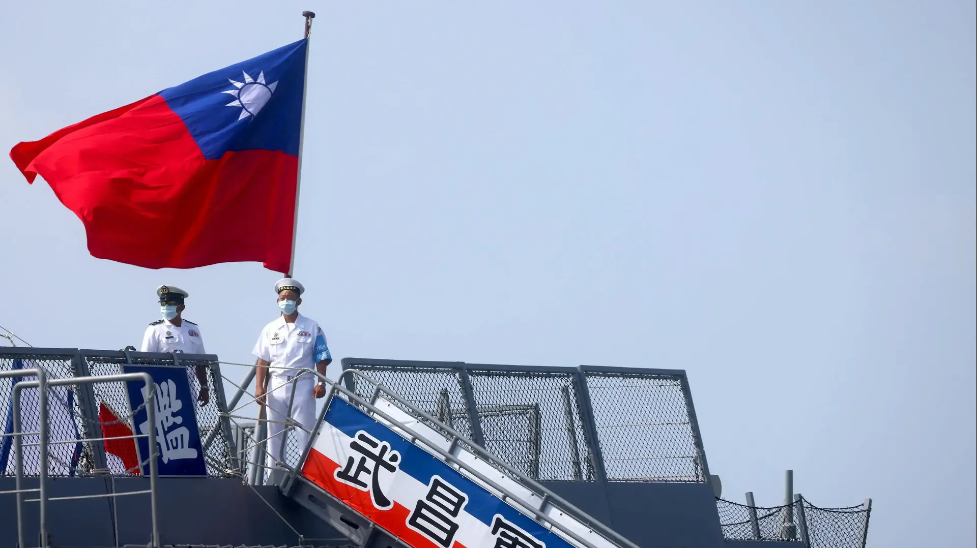 Two navy soldiers stand next to a Taiwanese flag as they welcome members of the public during a visit on the French-built ROCS Wu Chang (PFG-1207) frigate ahead of the National Day celebration in Kaohsiung, Taiwan, October 9, 2021. REUTERS/Ann Wang
