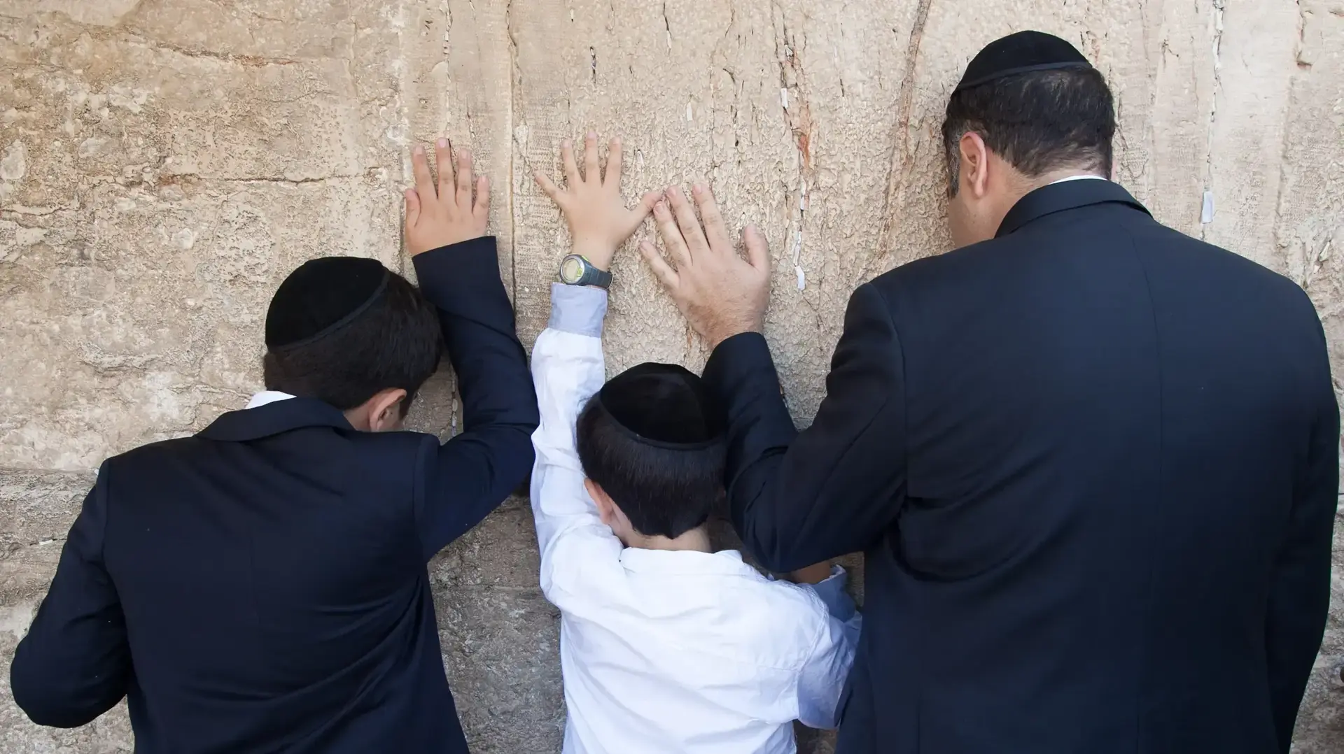 אב יהודי עם שני בניו מתפללים בכותל המערבי אב יהודי עם שני בניו מתפללים בכותל המערבי