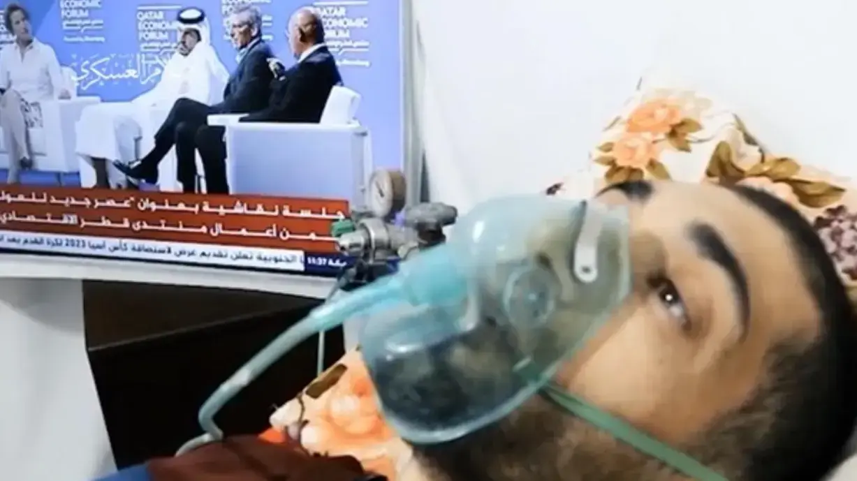 צילום מסך מהתיעוד של השבוי הישראלי בעזה הישאם א-סייד, כשברקע שידור של הפורום הכלכלי בקטאר שהתקיים ב-20-22 ביוני 2022, 28 ביוני 2022 צילום מסך מהתיעוד של השבוי הישראלי בעזה הישאם א-סייד, כשברקע שידור של הפורום הכלכלי בקטאר שהתקיים ב-20-22 ביוני 2022, 28 ביוני 2022