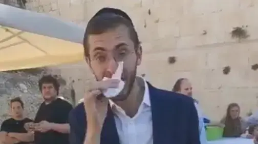צעיר חרדי מקנח את אפו כשהוא מבזב ומחלל  את כתבי הקודש
