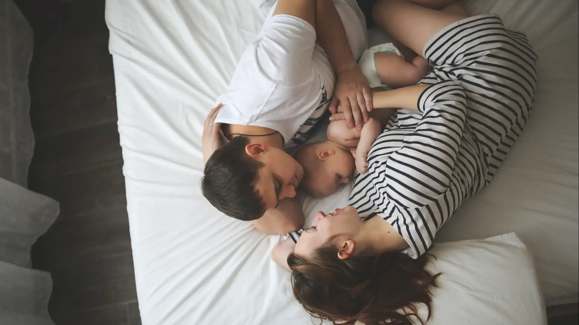 הורים ותינוקם שוכבים על המיטה הורים ותינוקם שוכבים על המיטה