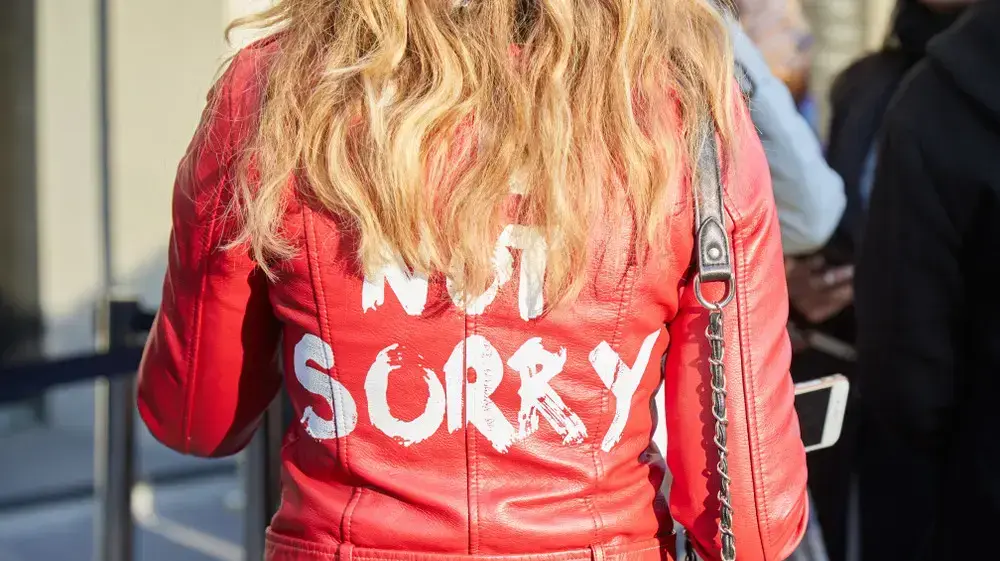 אישה עם ג'קט עור אדום והכיתוב sorry not sorry אישה עם ג'קט עור אדום והכיתוב sorry not sorry