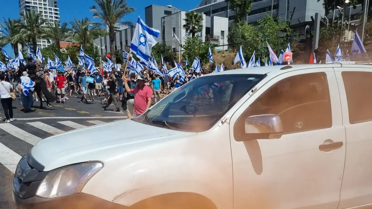 יום השיבושים: מחאות נגד המהפכה המשפטית ברחבי הארץ. מוחה הצית אבוקה מתחת לניידת משטרה בצומת קפלן דרך ונעצר בגין בחשד להפרת הסדר. 11 ביולי 2023 יום השיבושים: מחאות נגד המהפכה המשפטית ברחבי הארץ. מוחה הצית אבוקה מתחת לניידת משטרה בצומת קפלן דרך ונעצר בגין בחשד להפרת הסדר. 11 ביולי 2023