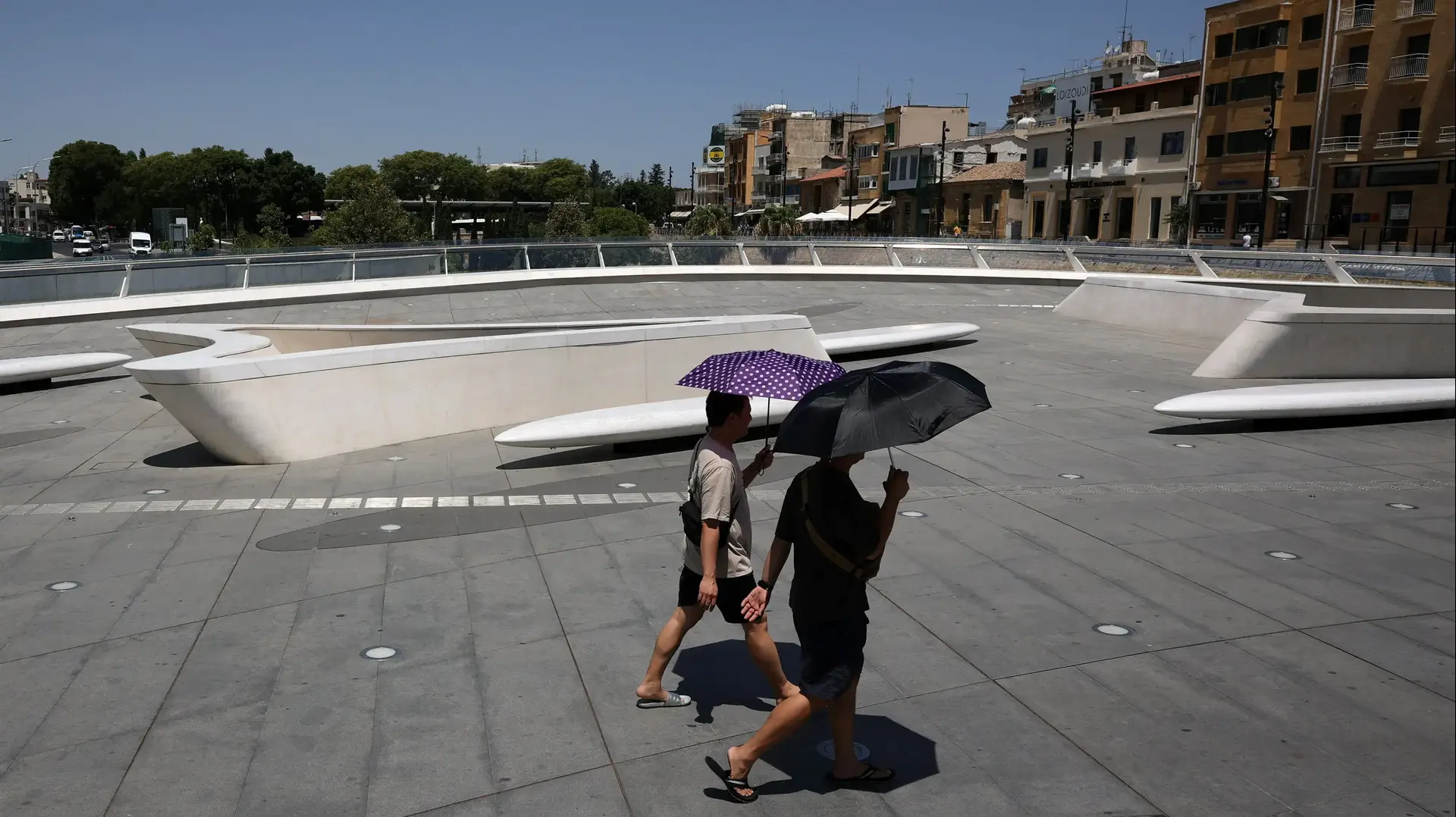 גברים מסתתרים תחת שמשייה עקב גם החום בניקוסיה, קפריסין גברים מסתתרים תחת שמשייה עקב גם החום בניקוסיה, קפריסין