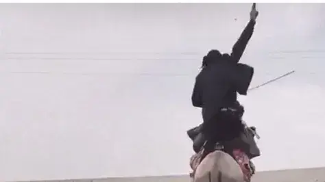 צעיר רכוב על גמל יורה בנשק צעיר רכוב על גמל יורה בנשק
