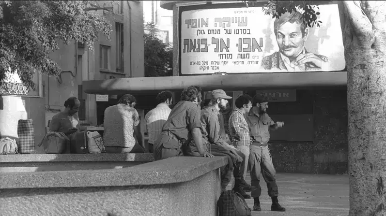חיילים מחכים לאיסוף, וברקע כרזת הסרט "אבו אל בנאת", 6 באוקטובר 1973 חיילים מחכים לאיסוף, וברקע כרזת הסרט "אבו אל בנאת", 6 באוקטובר 1973