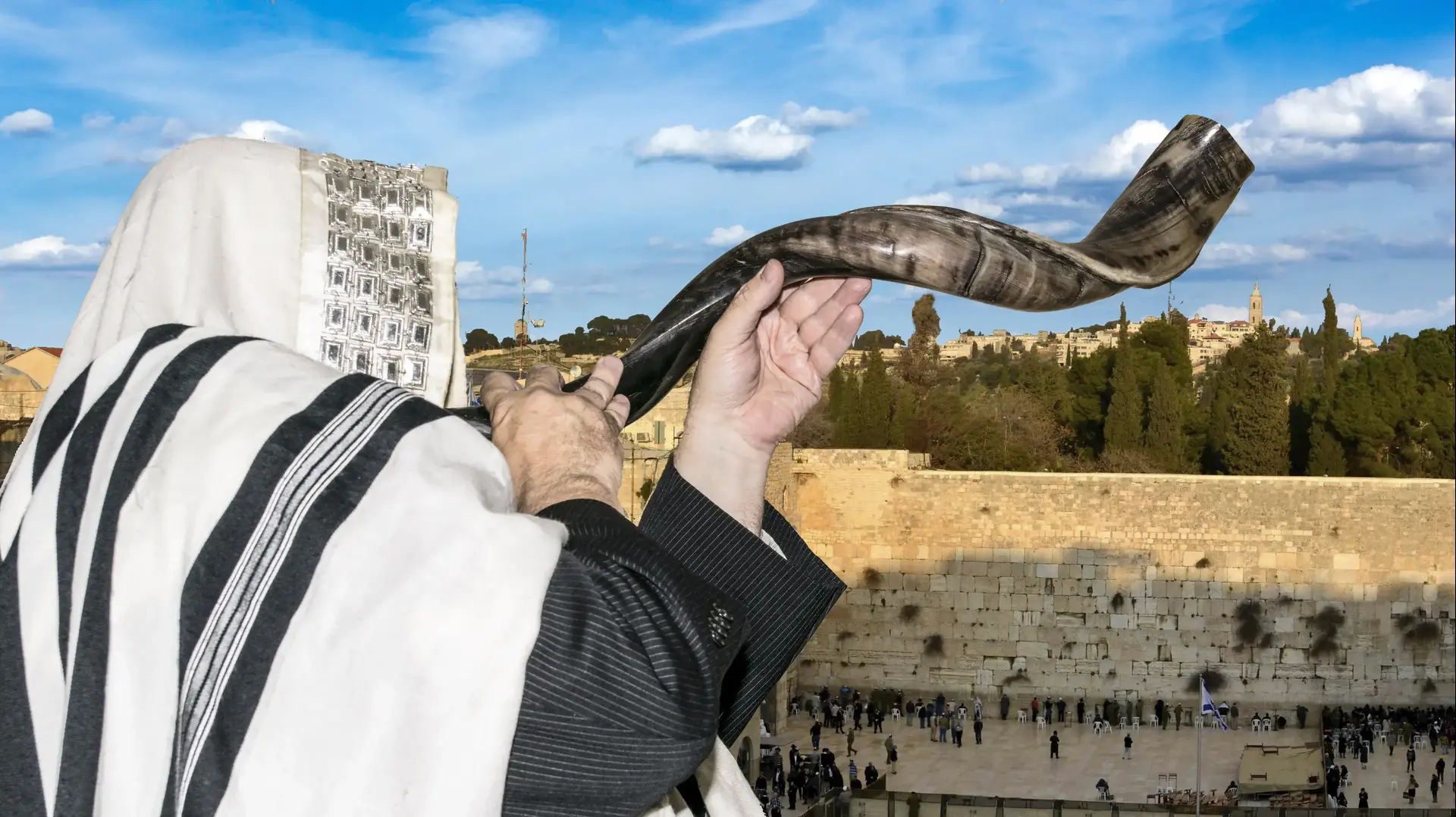 גבר יהודי חרדי תוקע בשופר על רקע הכותל המערבי