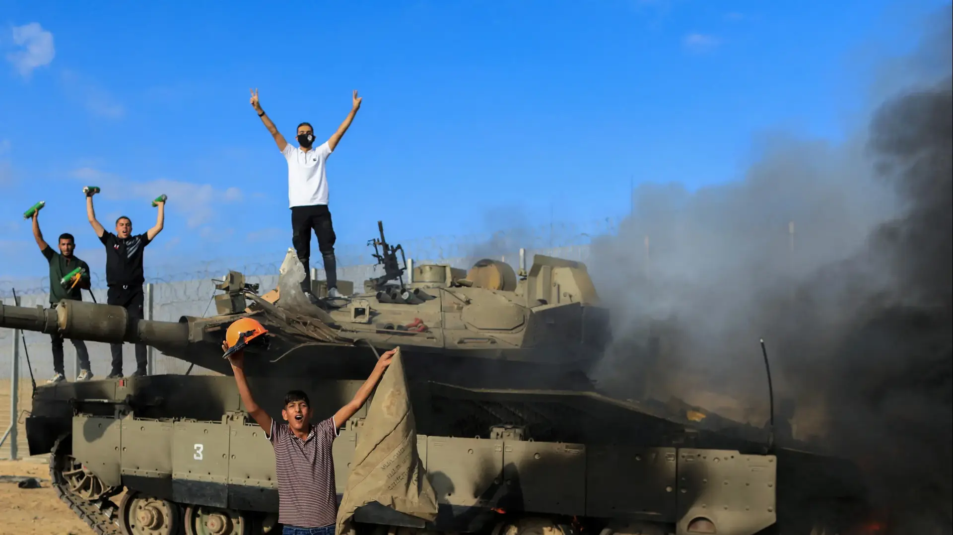 תושבים ברצועת עזה חוגגים על טנק שרוף של צה"ל בסמוך לגדר, 7 באוקטובר 2023 תושבים ברצועת עזה חוגגים על טנק שרוף של צה"ל בסמוך לגדר, 7 באוקטובר 2023