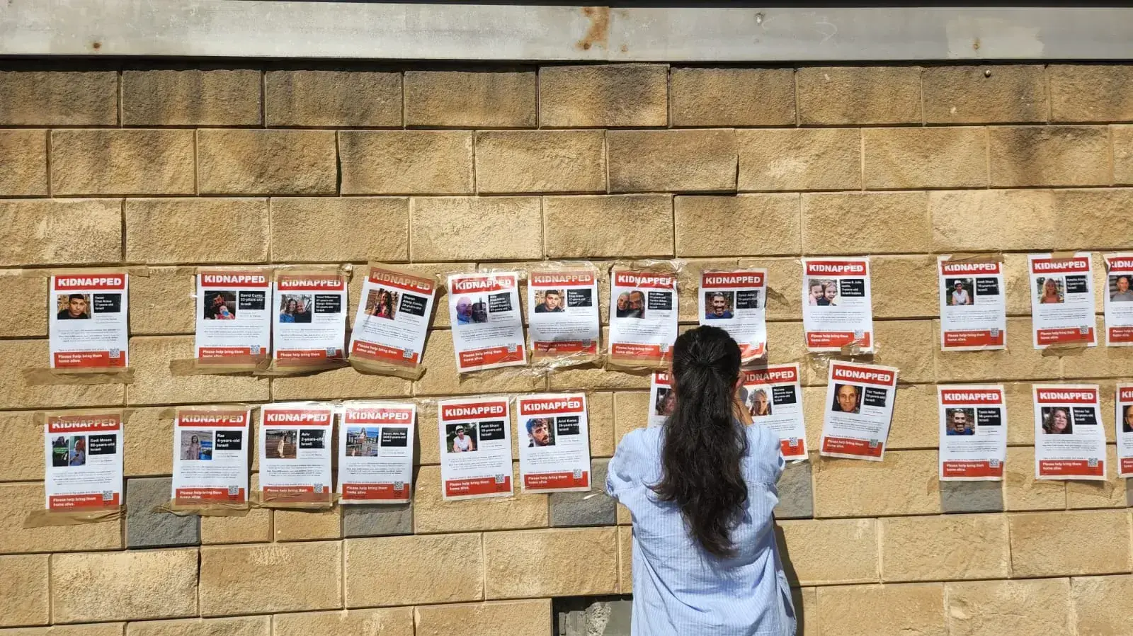 הדבקת תמונות החטופים על הקיר בקריה הדבקת תמונות החטופים על הקיר בקריה