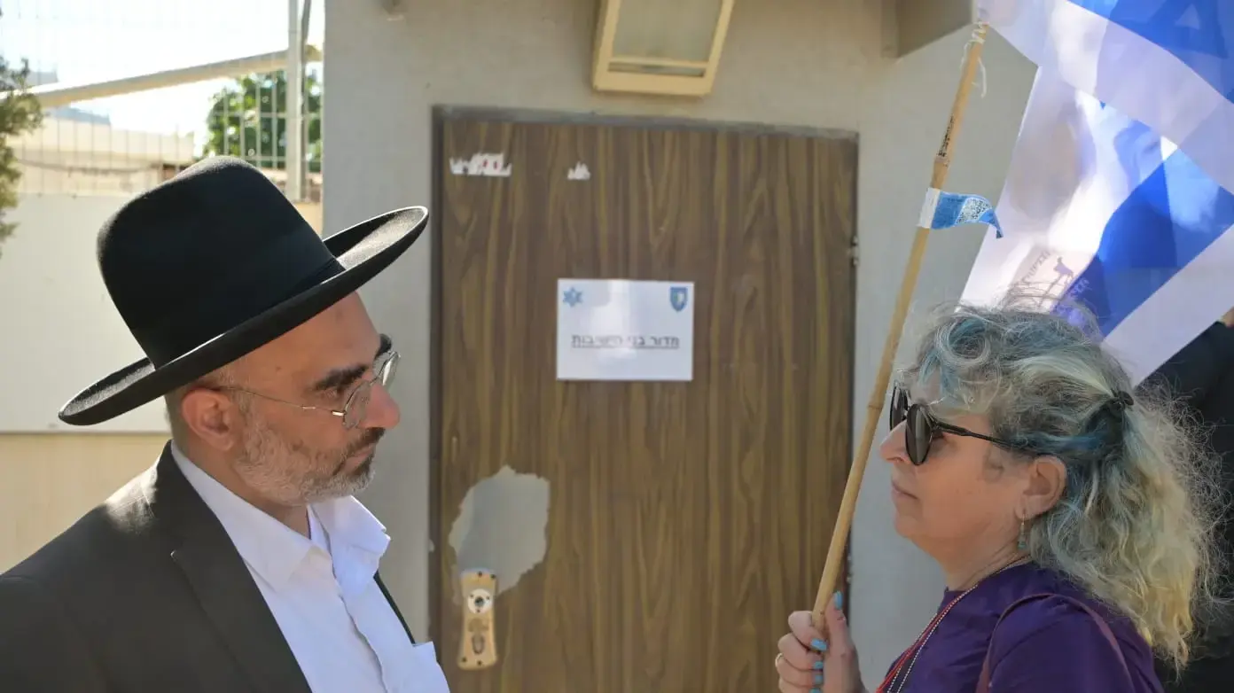 מפגינה ב"אמהות בחזית" על שירות שווה לכולם מדברת עם חרדי בכניסה למדור בני ישיבות מפגינה ב"אמהות בחזית" על שירות שווה לכולם מדברת עם חרדי בכניסה למדור בני ישיבות