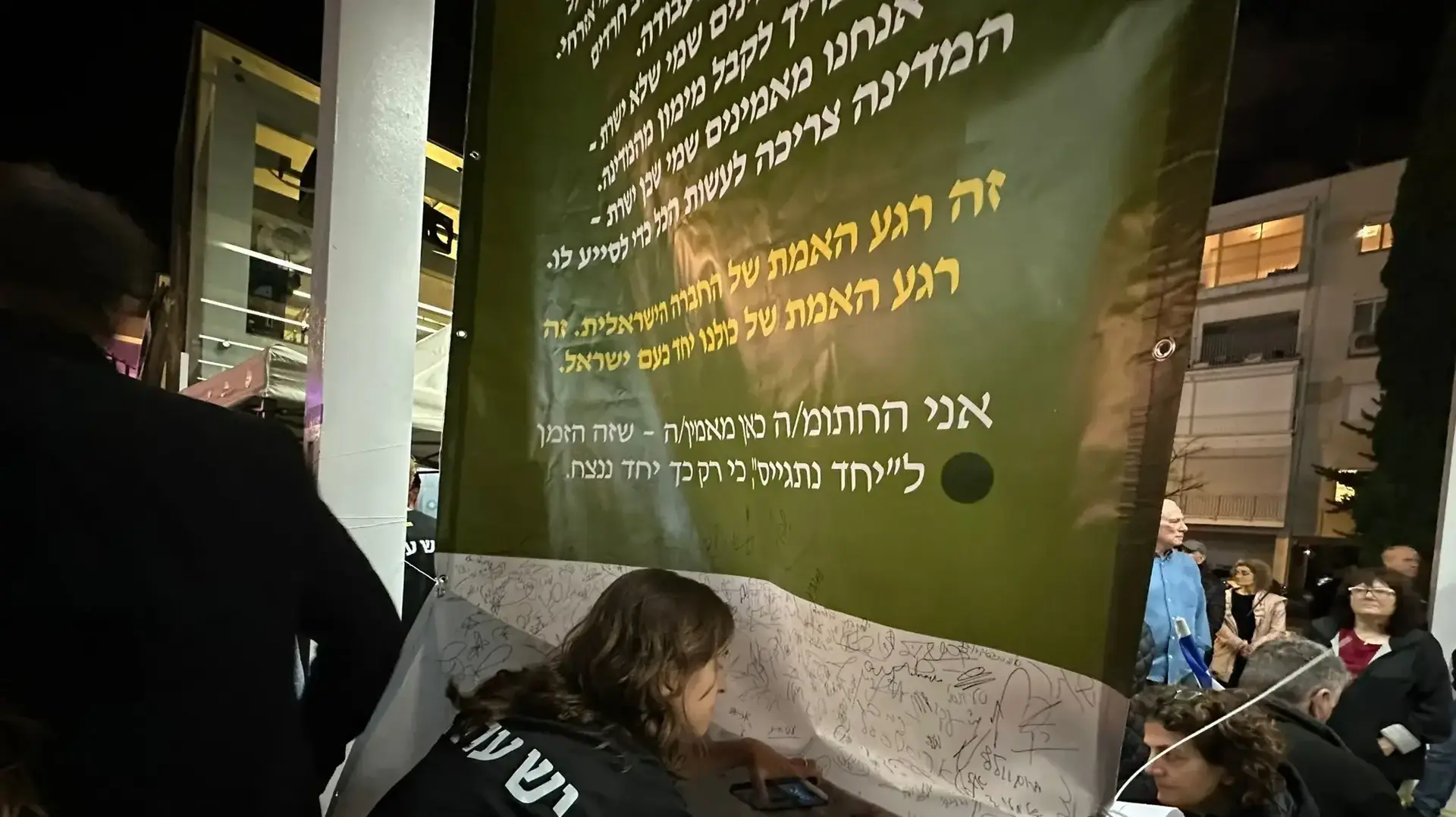 מפגינים חותמים על כרזה ובה עצומה למען שיוויון בנטל, בהפגנה בכיכר הבימה בתל אביב, 14 במרץ 2024 מפגינים חותמים על כרזה ובה עצומה למען שיוויון בנטל, בהפגנה בכיכר הבימה בתל אביב, 14 במרץ 2024