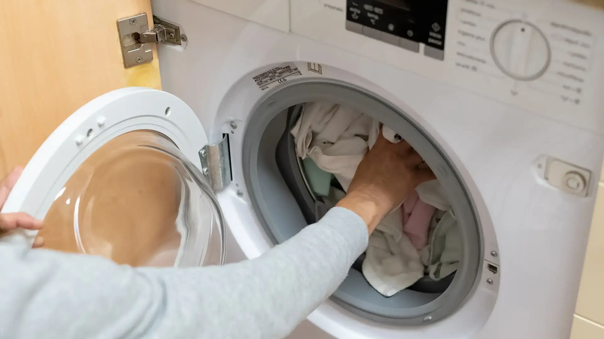 אישה מכניסה בגדים למכונת הכביסה אישה מכניסה בגדים למכונת הכביסה