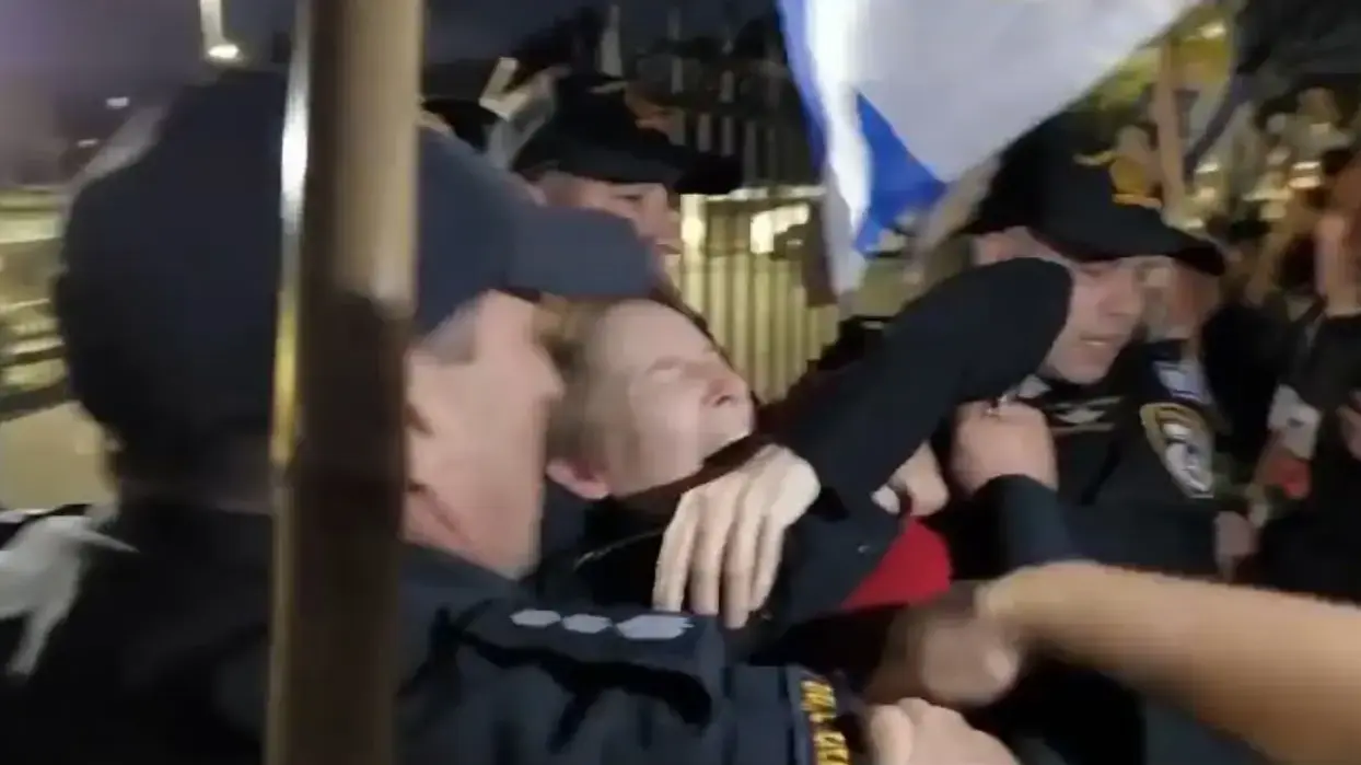 שוטר עוצר מפגינה בכוחניות בקיסריה 18 באפריל 2024
