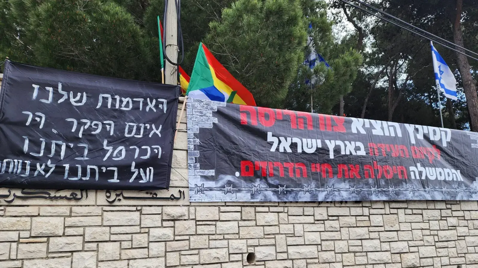 שלט שנתלה על בית העלמין הצבאי במהלך טקס יום הזיכרון בעוספיא, 13 במאי 2024 שלט שנתלה על בית העלמין הצבאי במהלך טקס יום הזיכרון בעוספיא, 13 במאי 2024