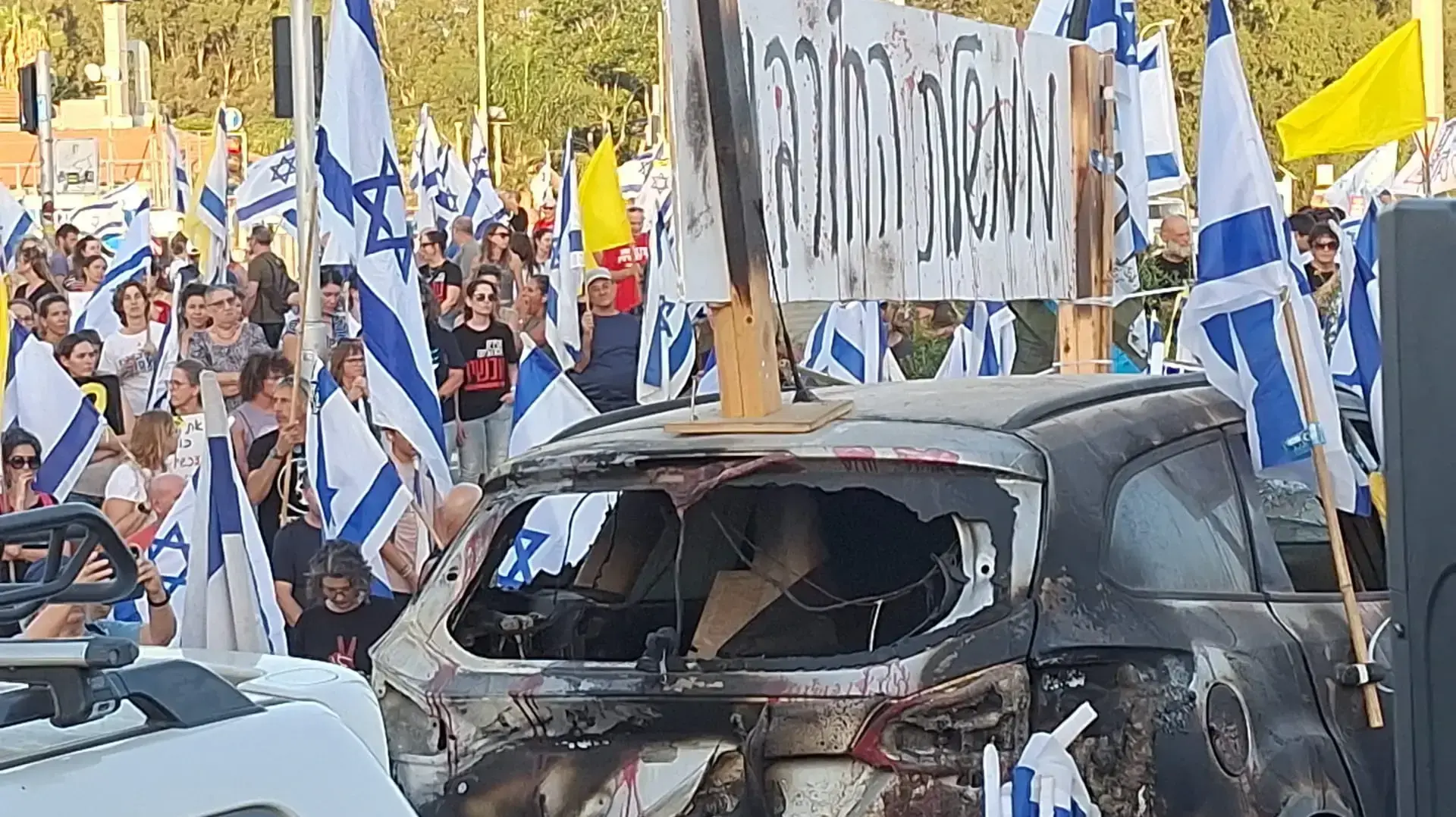 מיצג רכב שרוף של "אחים לנשק" בלב ההפגנה, כרכור, 29 ביוני 2024 מיצג רכב שרוף של "אחים לנשק" בלב ההפגנה, כרכור, 29 ביוני 2024