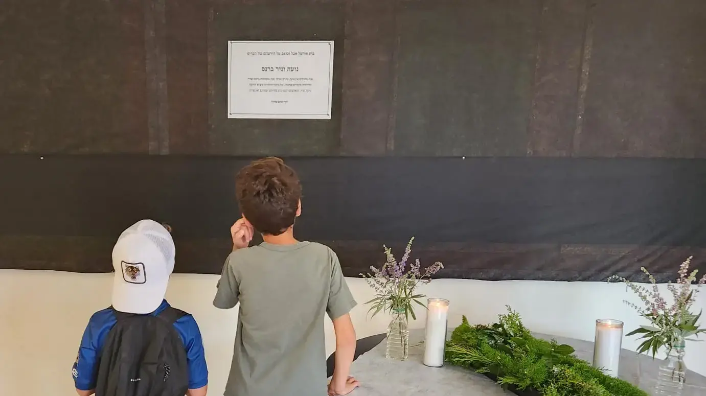 ילדים בקיבוץ אורטל מול מודעת האבל על מותם של בני הזוג ברנס ילדים בקיבוץ אורטל מול מודעת האבל על מותם של בני הזוג ברנס