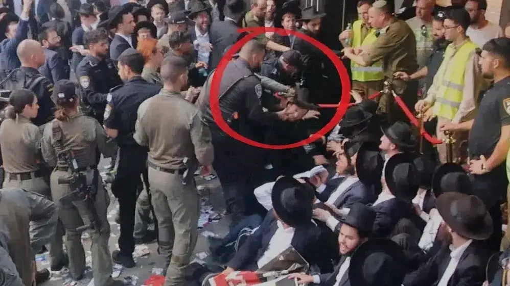 שוטר מושך בזקנים של מפגינים חרדים בהפגנה מחוץ לבית החייל בתל אביב, 30 ביולי 2024