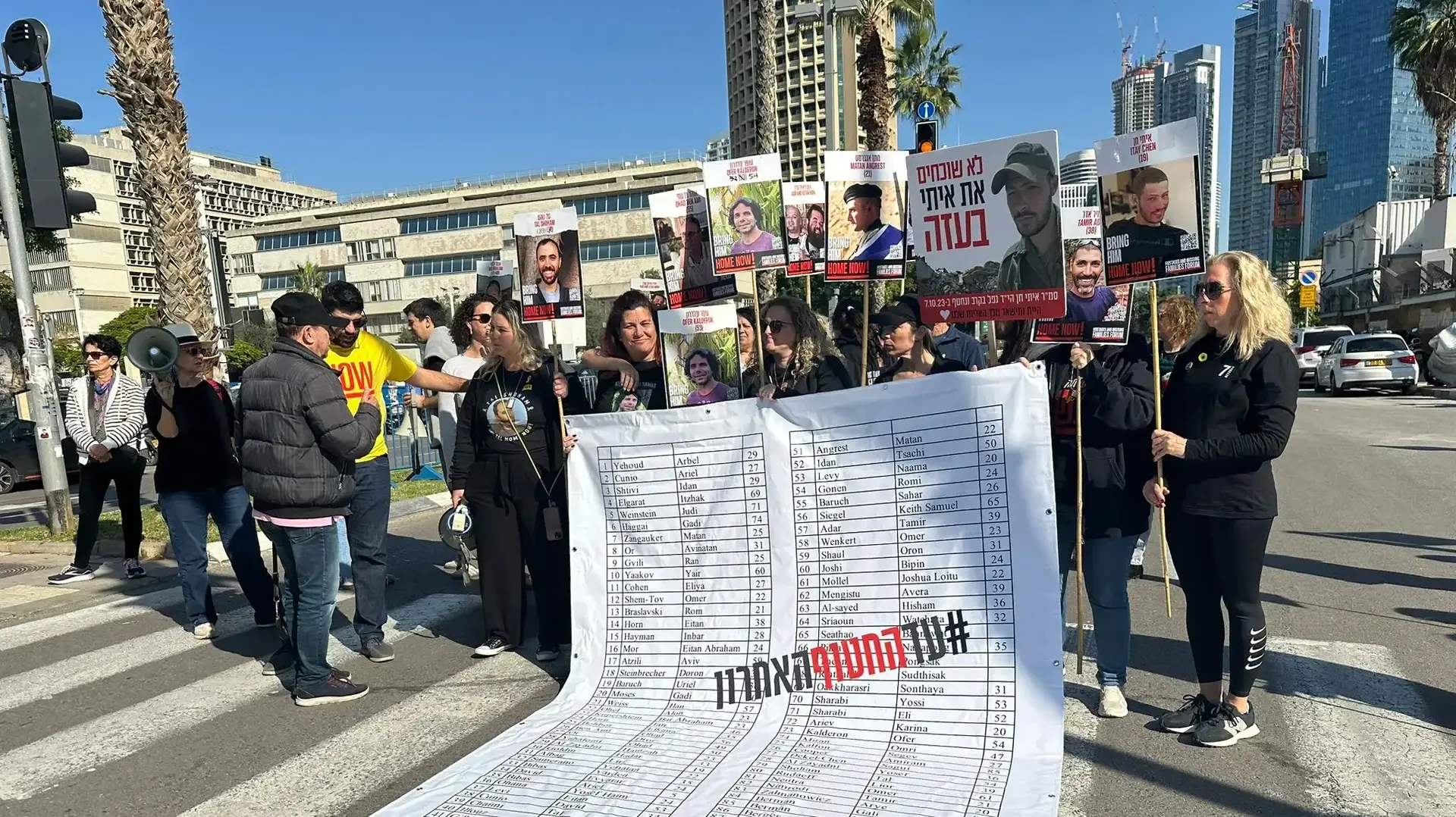 משפחות חטופים ופעילים חוסמים את רחוב שאול המלך עם רשימת ענק הכוללת את 100 החטופים, שער בסיס הקרייה, 7 בינואר 2025