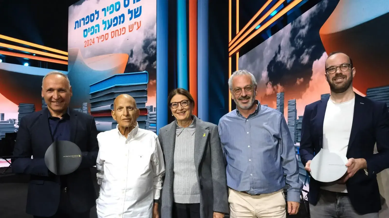 הזוכה בפרס הביכורים של פרס ספיר לספרות של מפעל הפיס לשנת 2024, איל חיות-מן על ספרו "מסכת תהום", מנכ"ל מפעל הפיס, עו"ד בני דרייפוס, נשיאת בית המשפט העליון בדימוס, השופטת אסתר חיות, יו"ר ועדת השיפוט של פרס ספיר, יו"ר מפעל הפיס, רו"ח אביגדור יצחקי והזוכה בפרס ספיר לספרות של מפעל הפיס לשנת 2024, יוסי אבני-לוי על ספרו "שלושה ימים בקיץ"