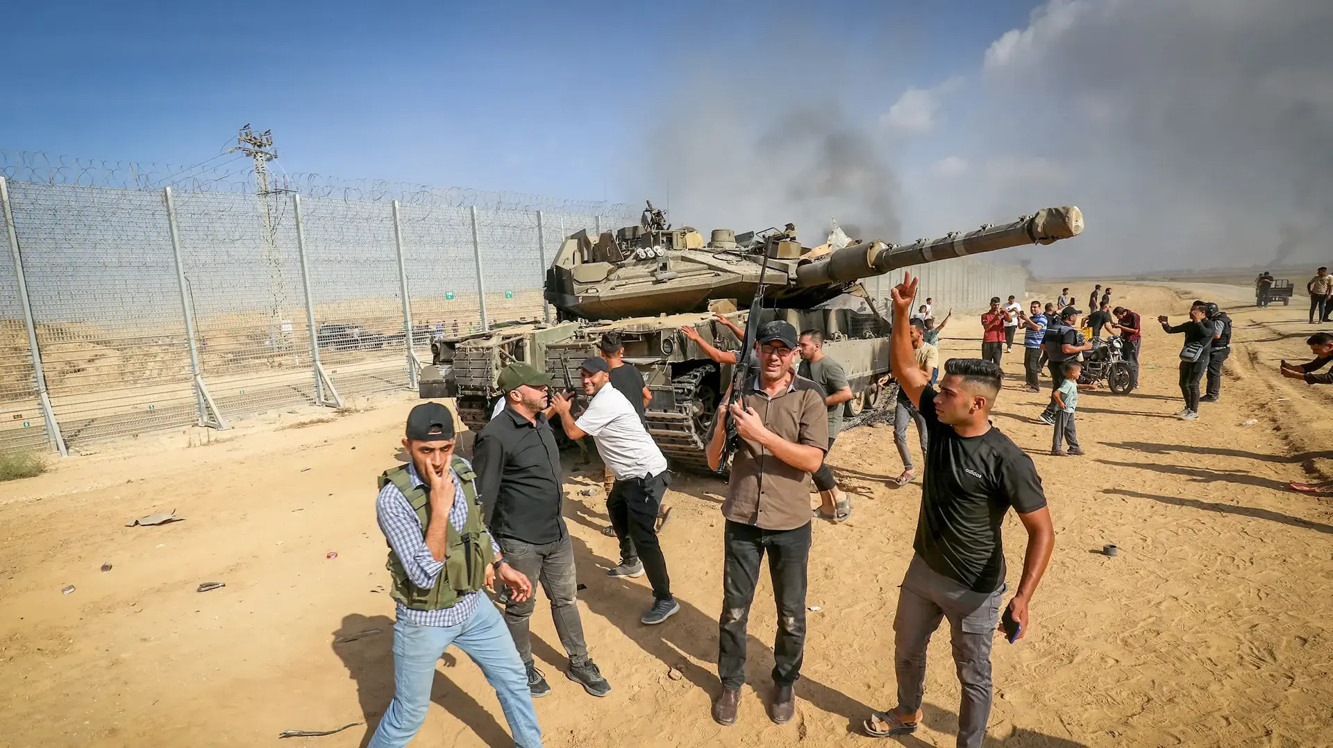 פלסטינים ליד טנק צה"ל שרוף קרוב לגדר הגבול עם חאן יונס, רצועת עזה, 7 באוקטובר 2023 פלסטינים ליד טנק צה"ל שרוף קרוב לגדר הגבול עם חאן יונס, רצועת עזה, 7 באוקטובר 2023
