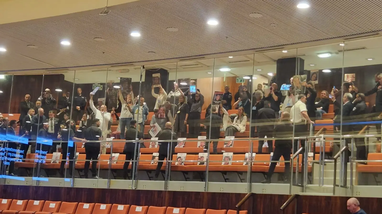משפחות "מועצת אוקטובר" ביציע המליאה מניפים תמונות של הנופלים, 3 במרץ 2025