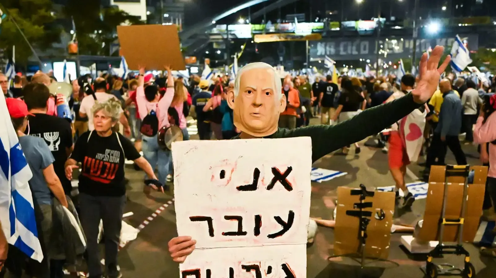 מפגין בדמות בנימין נתניהו עם שלט "אני עובר גיהינום", קפלן, 15 במרץ 2025 מפגין בדמות בנימין נתניהו עם שלט "אני עובר גיהינום", קפלן, 15 במרץ 2025