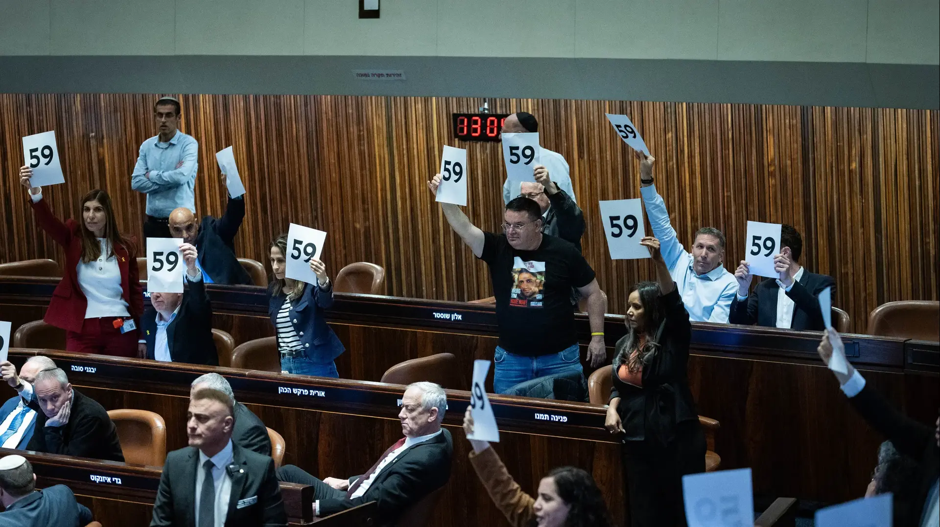 חברי האופוזיציה מניפים שלטי חטופים לאחר העברת תקציב המדינה, מליאת הכנסת, 25 במרץ 2025