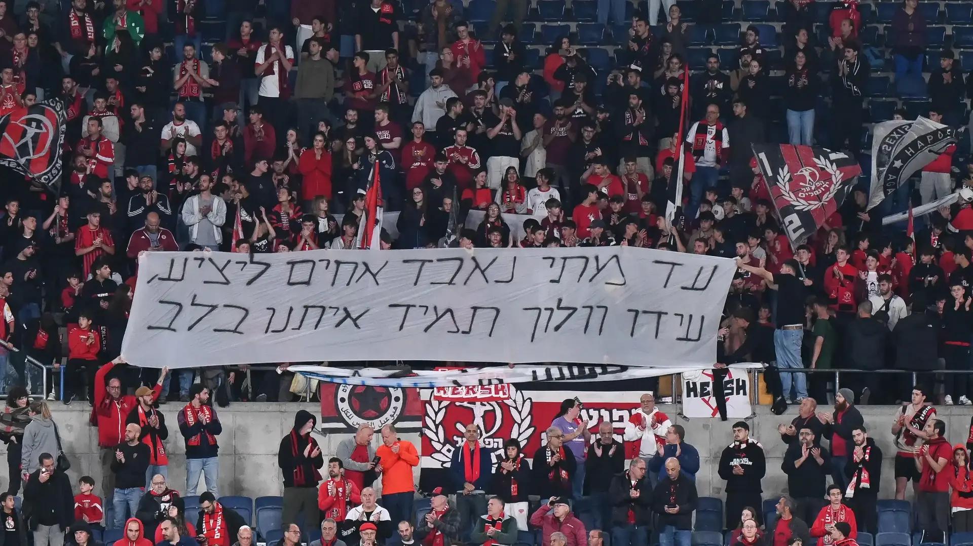 אוהדי הפועל ירושלים עם שלט לזכרו של עידו וולוך אוהדי הפועל ירושלים עם שלט לזכרו של עידו וולוך