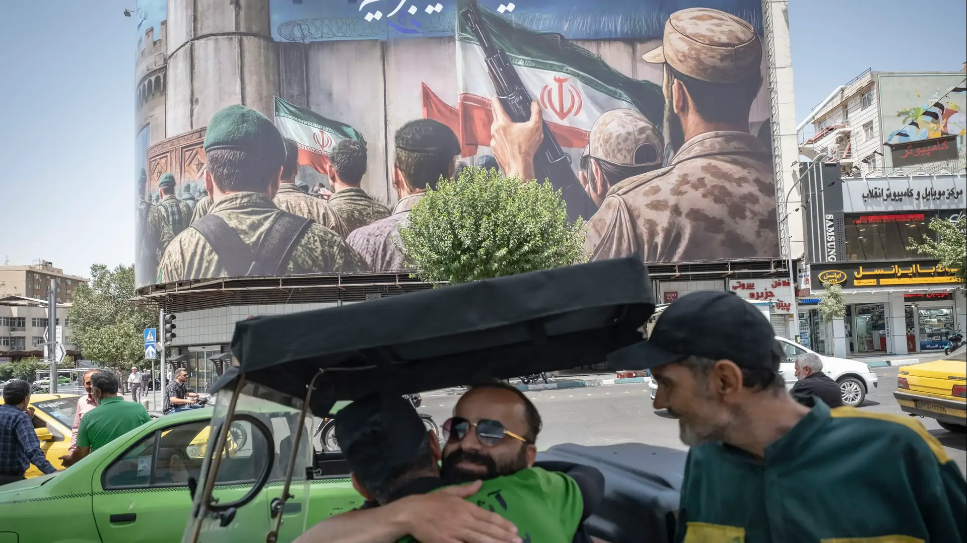 אנשים מתחבקים על רקע כרזה בטהראן, איראן, 24 ביוני 2025 אנשים מתחבקים על רקע כרזה בטהראן, איראן, 24 ביוני 2025